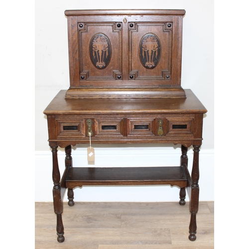 107 - An early 20th century oak desk with bureau top, 2 drawers to base under a fall front cupboard with 2... 