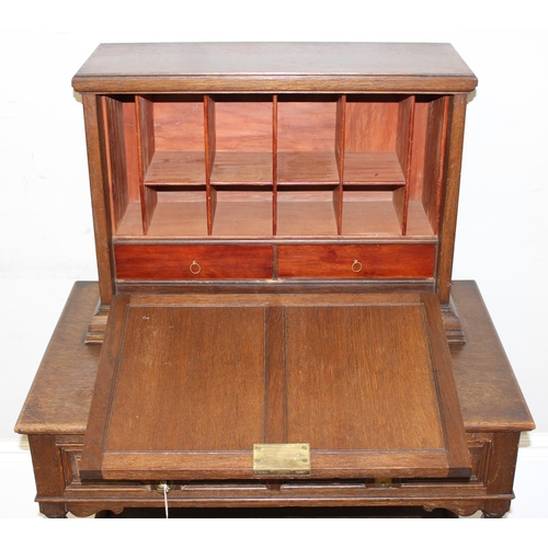 107 - An early 20th century oak desk with bureau top, 2 drawers to base under a fall front cupboard with 2... 