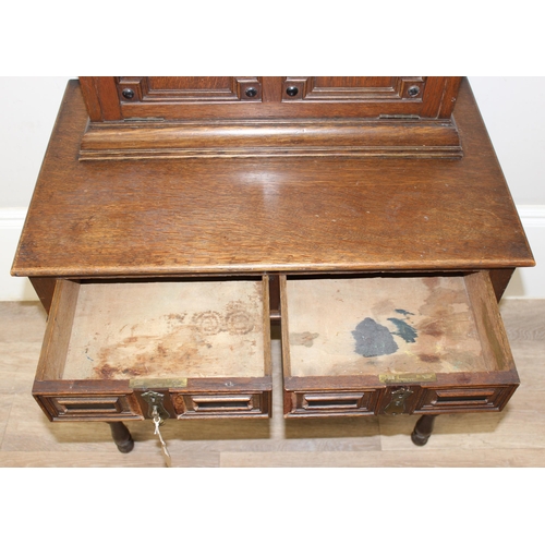 107 - An early 20th century oak desk with bureau top, 2 drawers to base under a fall front cupboard with 2... 