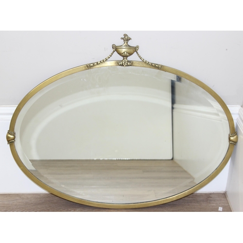 394 - A vintage brass framed oval wall mirror with urn and swag decoration, approx 81cm x 62cm