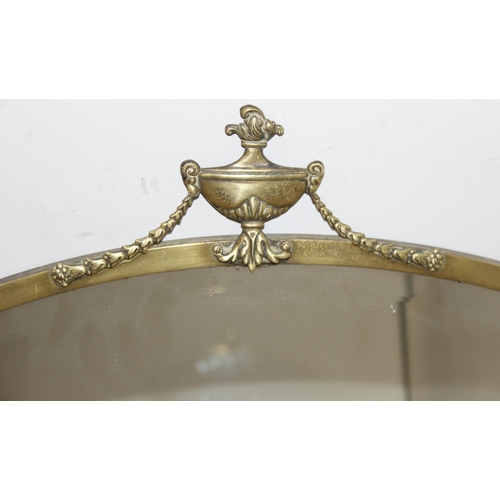 394 - A vintage brass framed oval wall mirror with urn and swag decoration, approx 81cm x 62cm