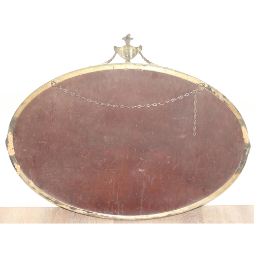 394 - A vintage brass framed oval wall mirror with urn and swag decoration, approx 81cm x 62cm