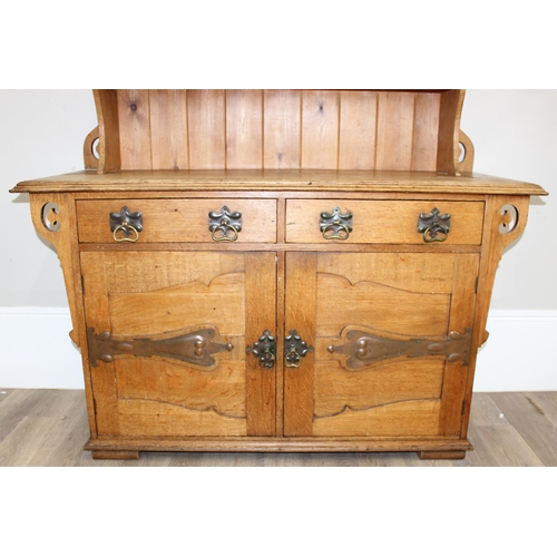 11 - In the manner of Liberty of London, an Arts & Crafts period light oak dresser, with highly decorativ... 