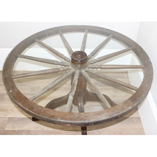 62 - A vintage glass topped table formed from a cartwheel with iron rim, approx 120cm in diameter x 75cm ... 