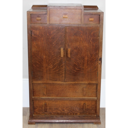 69 - An Art Deco period oak side cabinet with 3 stepped drawers over 2 cupboards over 2 further drawers, ... 