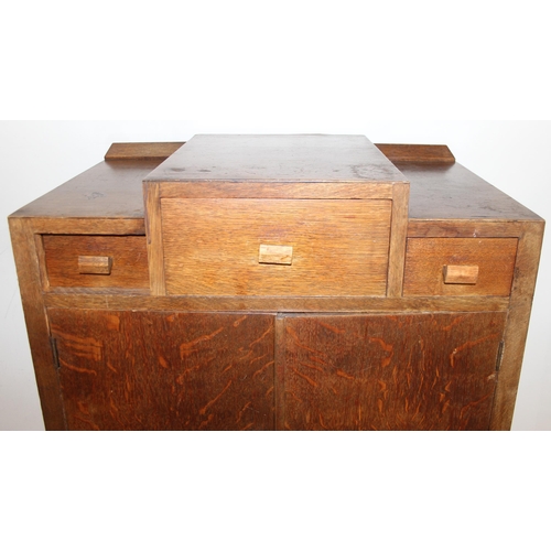 69 - An Art Deco period oak side cabinet with 3 stepped drawers over 2 cupboards over 2 further drawers, ... 