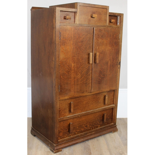 69 - An Art Deco period oak side cabinet with 3 stepped drawers over 2 cupboards over 2 further drawers, ... 