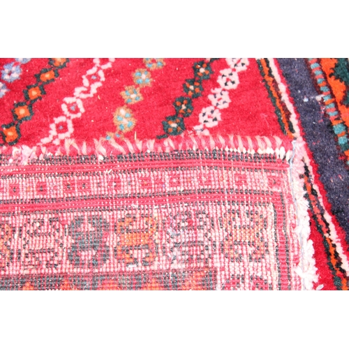 205 - A large vintage red ground rug decorated with a large geometric diamond pattern, possibly Caucasian,... 