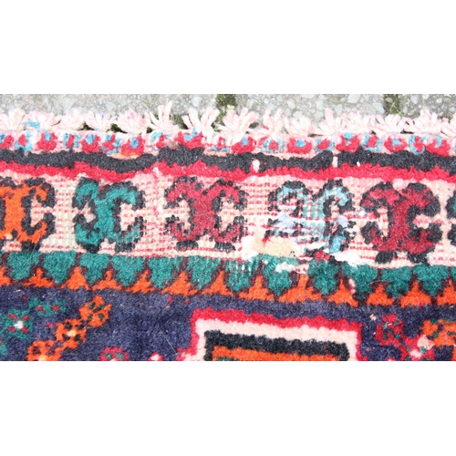 205 - A large vintage red ground rug decorated with a large geometric diamond pattern, possibly Caucasian,... 