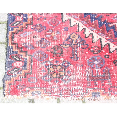 207 - A large vintage red ground rug with geometric patterns, worn, approx 200cm x 114cm