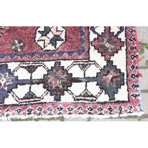 208 - A large vintage red ground and cream rug with geometric designs, worn, possibly Turkish, approx 295c... 