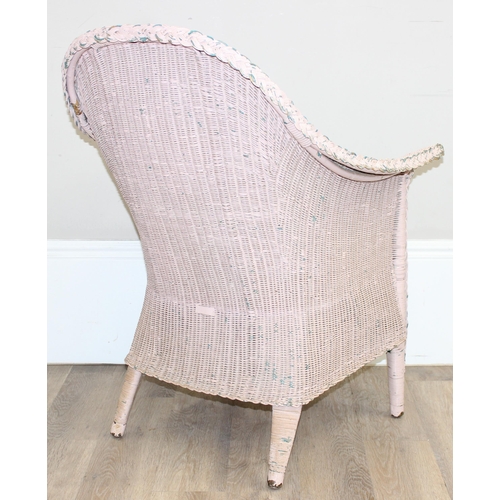 79 - A vintage woven armchair in the manner of Lloyd Loom, over painted label to back, salmon pink distre... 