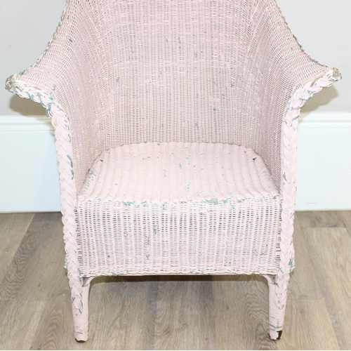 79 - A vintage woven armchair in the manner of Lloyd Loom, over painted label to back, salmon pink distre... 