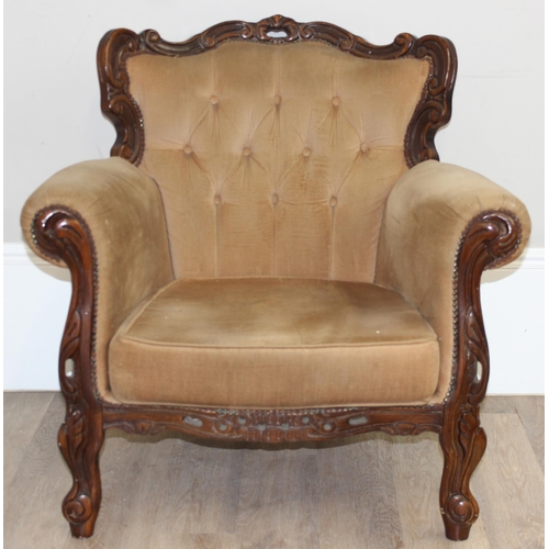 63 - An antique style button back low armchair with exposed carved wooden frame and gold upholstery, appr... 