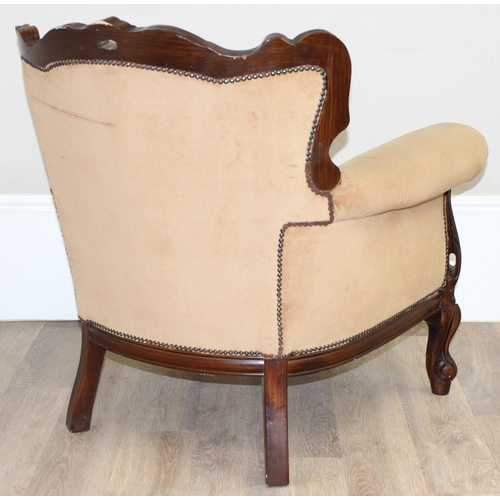 63 - An antique style button back low armchair with exposed carved wooden frame and gold upholstery, appr... 