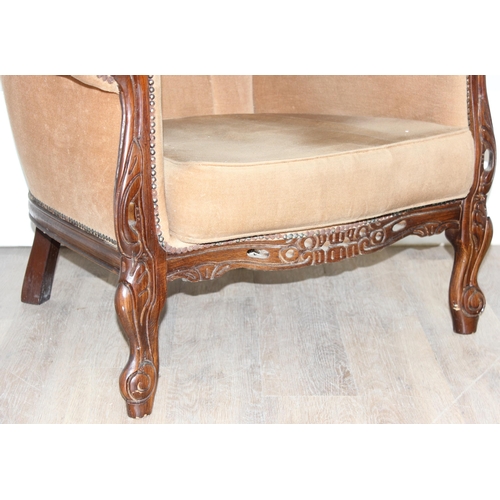 63 - An antique style button back low armchair with exposed carved wooden frame and gold upholstery, appr... 