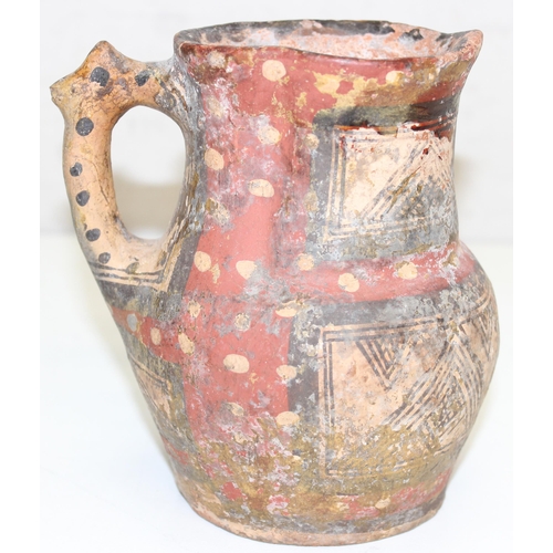 1455 - An unusual antique pottery jug with red spotted decoration and geometric painted decoration, approx ... 