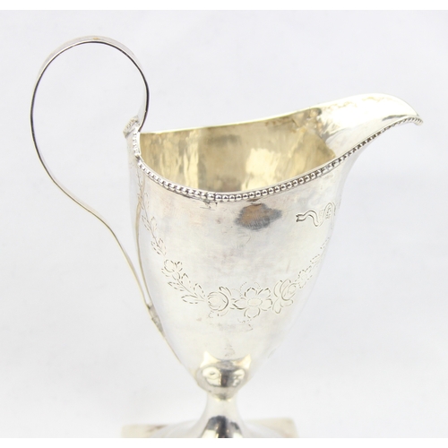 1081 - A Georgian silver helmet shaped cream jug with engraved decoration, marked for London 1787 with a ru... 