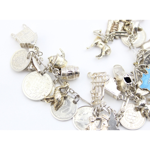 1103 - A vintage silver charm bracelet with a large qty of silver charms and coins, approx 16cm long, appro... 