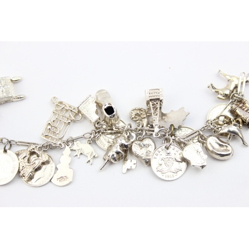 1103 - A vintage silver charm bracelet with a large qty of silver charms and coins, approx 16cm long, appro... 