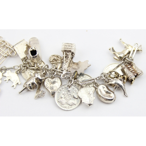 1103 - A vintage silver charm bracelet with a large qty of silver charms and coins, approx 16cm long, appro... 