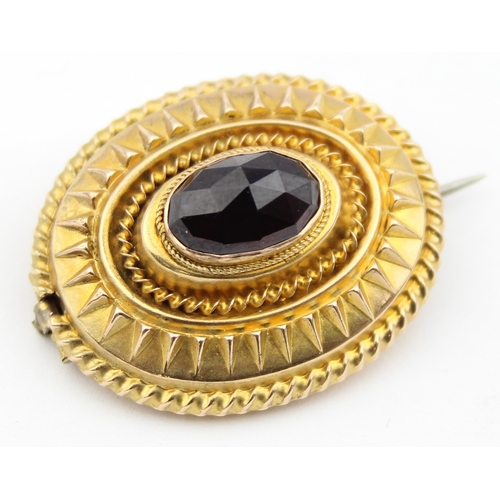 1137 - A Victorian 15ct gold brooch set with a facet cut red stone, possibly a Garnet, seemingly unmarked b... 