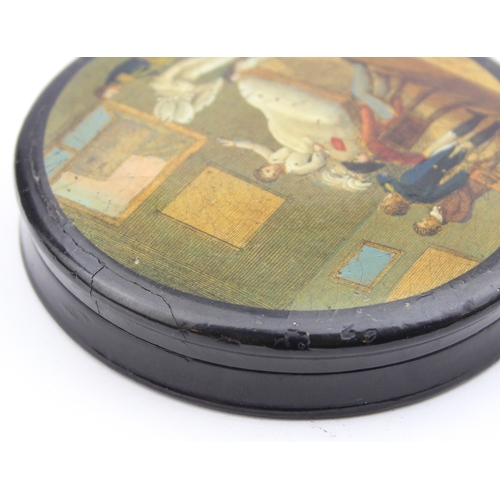 1451 - An early 19th century lacquered papier mache circular snuff box printed with a crowded tavern scene,... 