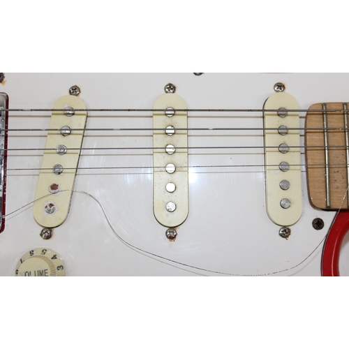 752 - A vintage electric guitar in the shape of a Fender Stratocaster, red wooden body, seemingly unmarked... 