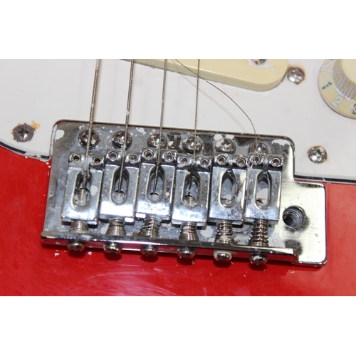 752 - A vintage electric guitar in the shape of a Fender Stratocaster, red wooden body, seemingly unmarked... 