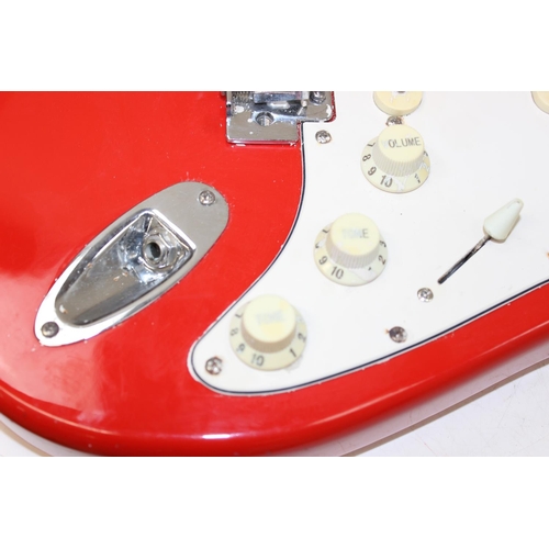 752 - A vintage electric guitar in the shape of a Fender Stratocaster, red wooden body, seemingly unmarked... 