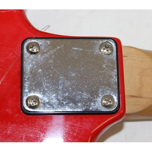 752 - A vintage electric guitar in the shape of a Fender Stratocaster, red wooden body, seemingly unmarked... 