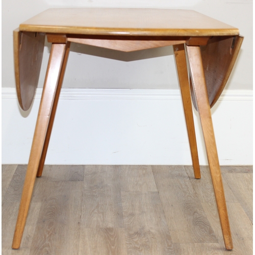 28 - A retro Ercol circular or oval topped drop leaf dining table, approx 65cm wide (124 cm extended) x 1... 