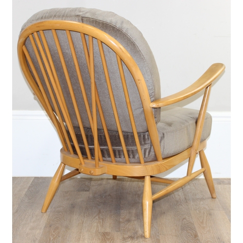 33 - A retro Ercol armchair believed to be a model 203 with sage green colour cushions, black and gold la... 