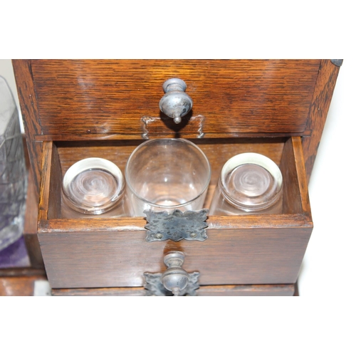 299A - A vintage oak tantalus of unusual form with single bottle and 3 drawers, the decanter a replacement,... 