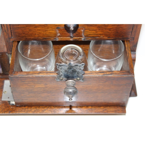 299A - A vintage oak tantalus of unusual form with single bottle and 3 drawers, the decanter a replacement,... 