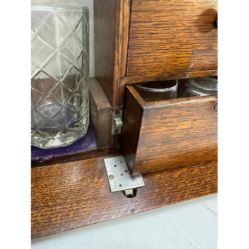 299A - A vintage oak tantalus of unusual form with single bottle and 3 drawers, the decanter a replacement,... 