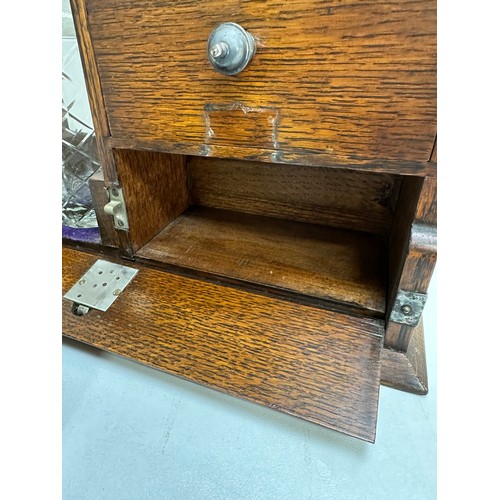 299A - A vintage oak tantalus of unusual form with single bottle and 3 drawers, the decanter a replacement,... 