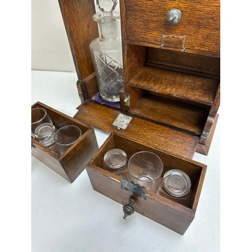 299A - A vintage oak tantalus of unusual form with single bottle and 3 drawers, the decanter a replacement,... 