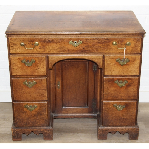 38 - A Georgian oak kneehole desk, one long drawer over six short drawers with cupboard, brass fittings a... 