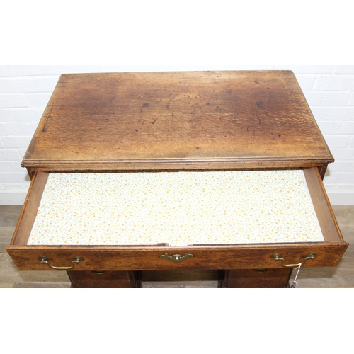 38 - A Georgian oak kneehole desk, one long drawer over six short drawers with cupboard, brass fittings a... 