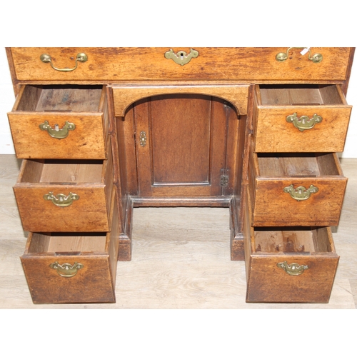 38 - A Georgian oak kneehole desk, one long drawer over six short drawers with cupboard, brass fittings a... 