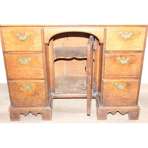 38 - A Georgian oak kneehole desk, one long drawer over six short drawers with cupboard, brass fittings a... 