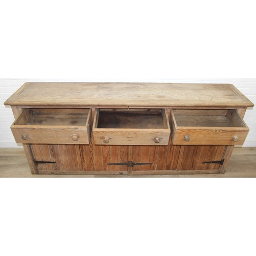 61 - A large antique pine dresser base comprising of three deep drawers with turned handles over four cup... 