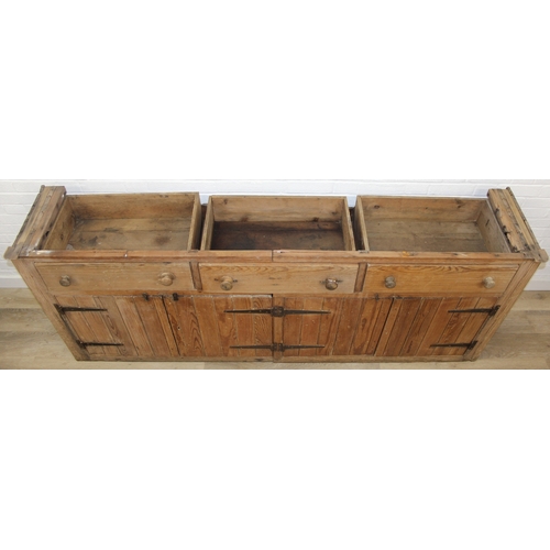 61 - A large antique pine dresser base comprising of three deep drawers with turned handles over four cup... 