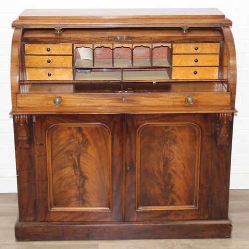 183 - A Victorian mahogany rolltop desk with fitted interior above a cupboard, plinth base, brass mounts, ... 