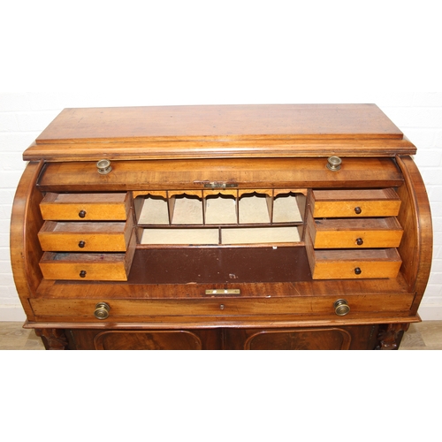 183 - A Victorian mahogany rolltop desk with fitted interior above a cupboard, plinth base, brass mounts, ... 