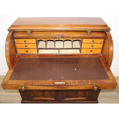 183 - A Victorian mahogany rolltop desk with fitted interior above a cupboard, plinth base, brass mounts, ... 