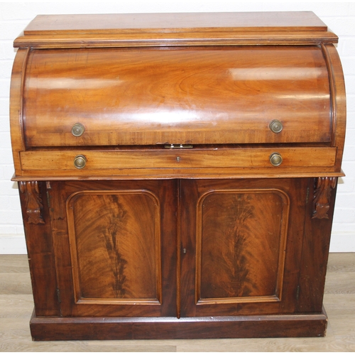 183 - A Victorian mahogany rolltop desk with fitted interior above a cupboard, plinth base, brass mounts, ... 