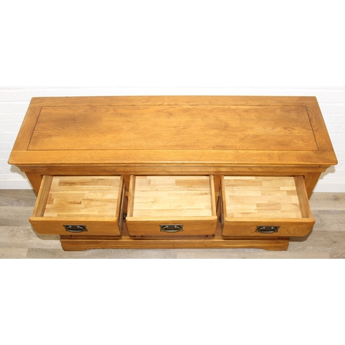 7 - A good quality modern light oak sideboard with three drawers over three cupboards, bronzed metal fit... 