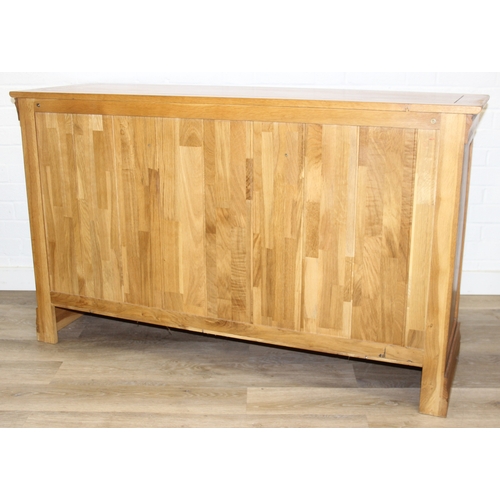 7 - A good quality modern light oak sideboard with three drawers over three cupboards, bronzed metal fit... 
